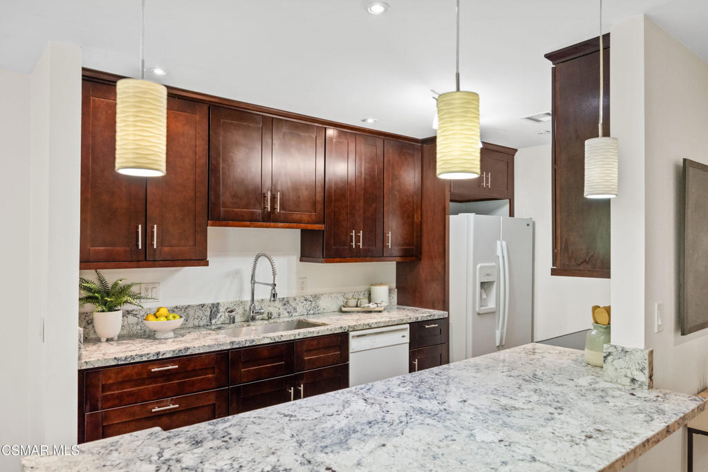 23637 Park Capri, Unit 36 Calabasas, CA 91302 - Photo 18 of 39 a kitchen with stainless steel appliances kitchen island granite countertop a refrigerator and cabinets