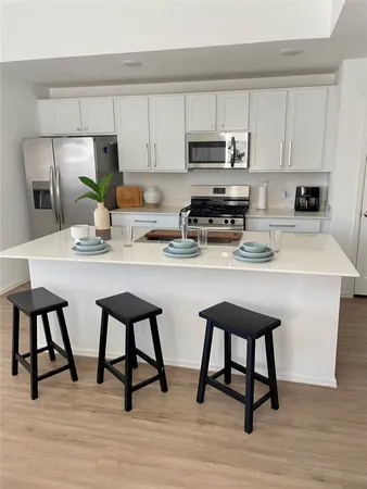 a kitchen with stainless steel appliances a white table and chairs in it