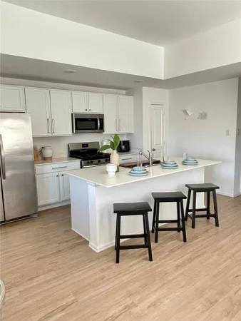 a kitchen with stainless steel appliances kitchen island granite countertop a table chairs sink and cabinets