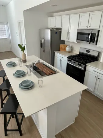 a kitchen with stainless steel appliances a table chairs and a refrigerator