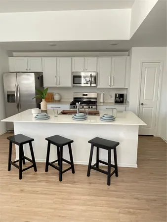 a kitchen with stainless steel appliances a table chairs microwave and sink