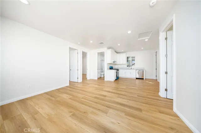 a view of kitchen and empty room with wooden floor