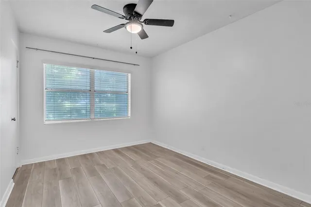 an empty room with a window and a ceiling fan