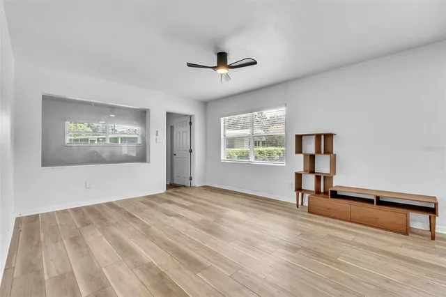 a view of an empty room with a window and wooden floor