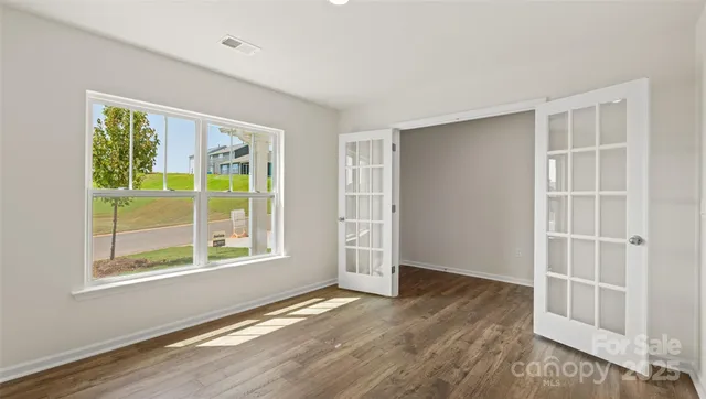 an empty room with wooden floor and windows