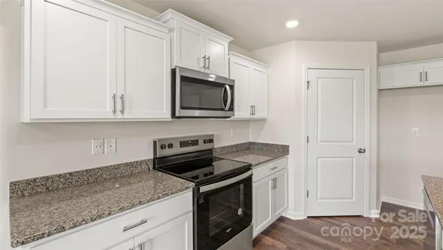 a kitchen with stainless steel appliances granite countertop white cabinets and a stove