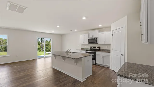 a kitchen with stainless steel appliances kitchen island granite countertop a stove and a refrigerator