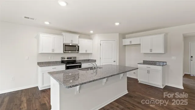 a kitchen with granite countertop a sink stove and refrigerator