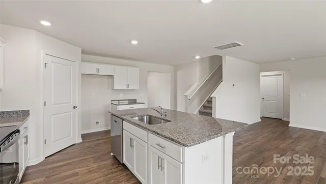 a kitchen that has a sink a stove and a wooden floor