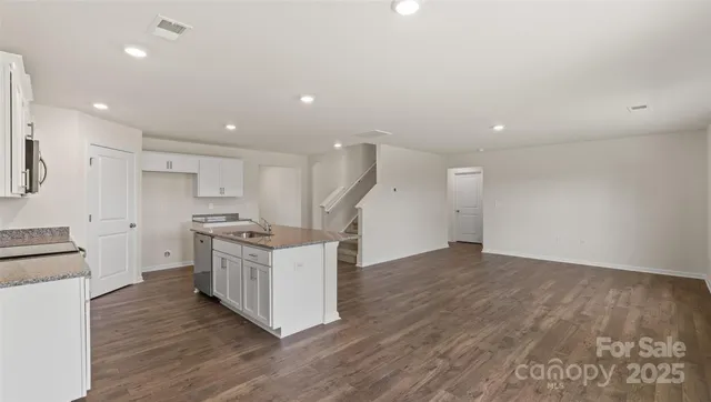 a kitchen with cabinets wooden floor and stainless steel appliances