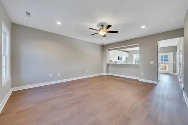 a view of an empty room with a window and wooden floor