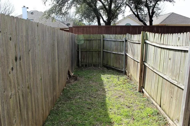 a view of a backyard with wooden fence and a large tree