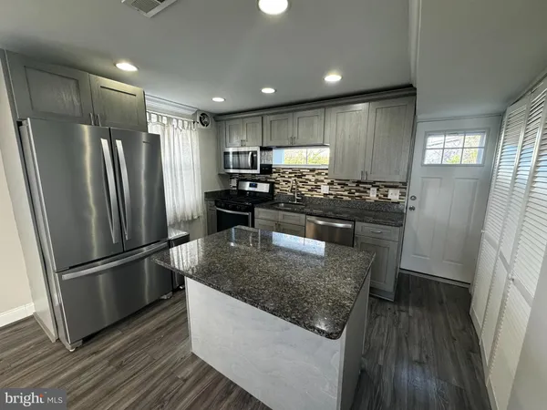 a kitchen with stainless steel appliances granite countertop a refrigerator a sink a stove a microwave and island
