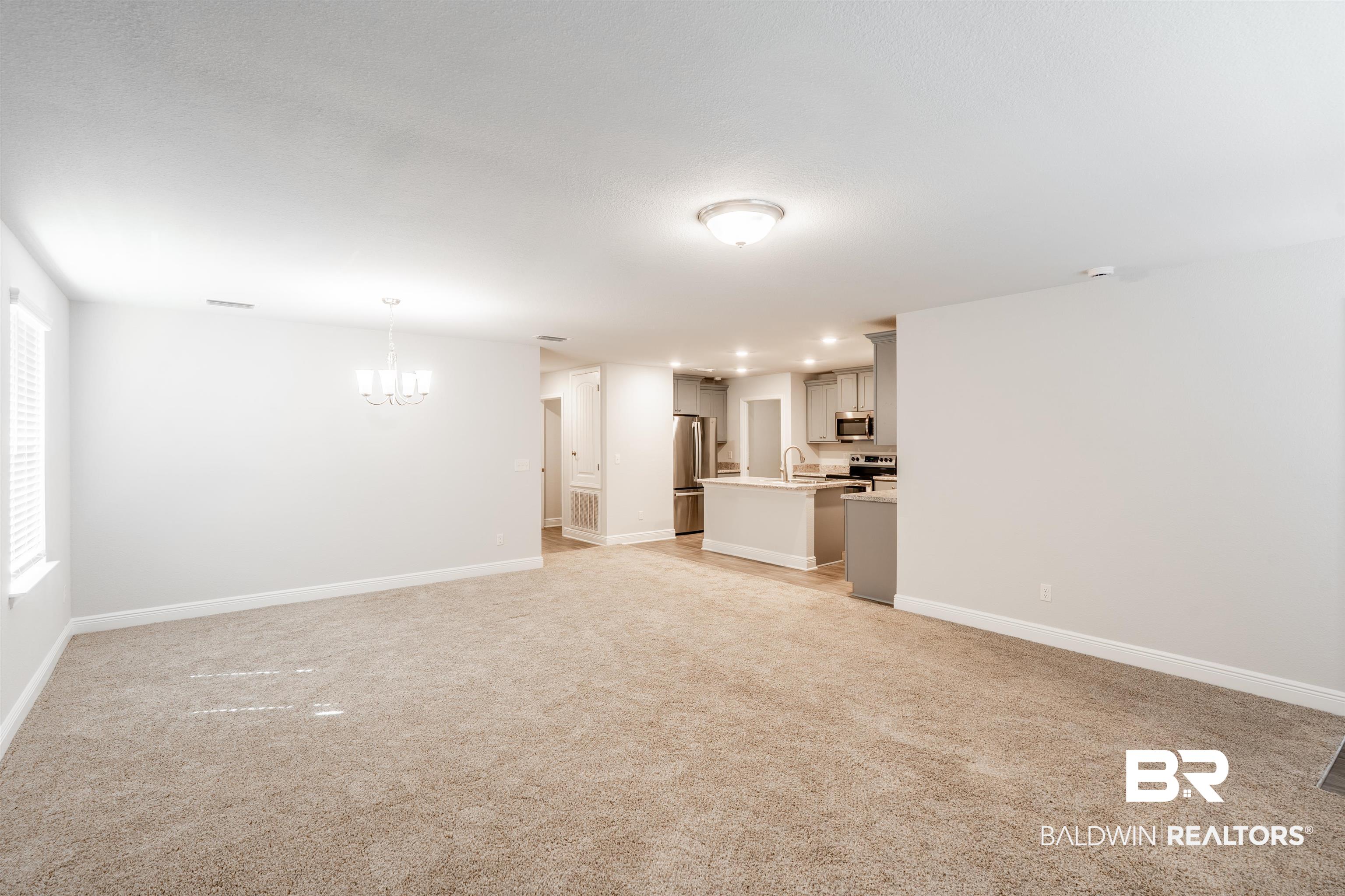 1906 Stonepine Drive South Semmes, AL 36575 - Photo 3 of 30 Unfurnished living room featuring light carpet and a chandelier