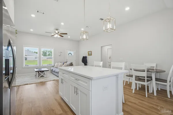 a very nice looking dining room with kitchen island stainless steel appliances a table chairs and a chandelier