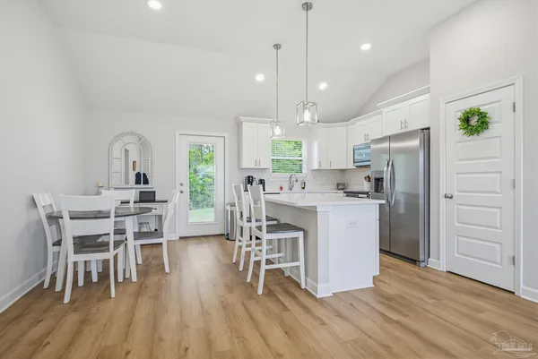 a kitchen with a dining table chairs refrigerator and microwave