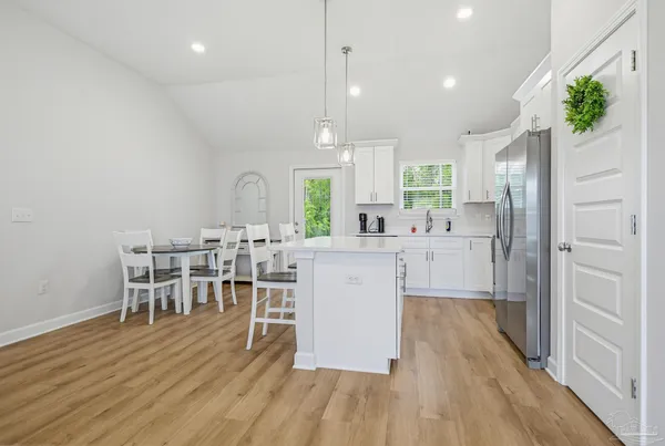 a kitchen with kitchen island a dining table chairs and wooden floor