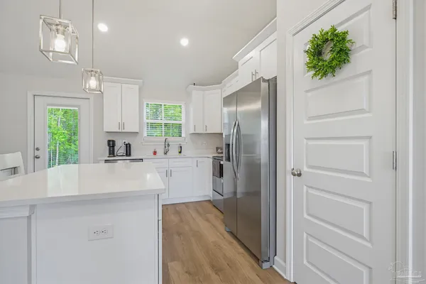 a kitchen with kitchen island white cabinets and refrigerator