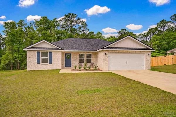 a front view of a house with yard plants and outdoor seating