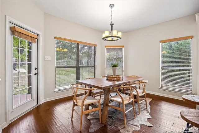 a kitchen with stainless steel appliances granite countertop a sink dishwasher a refrigerator and white cabinets with wooden floor