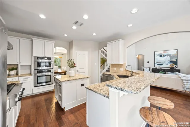 a kitchen with a center island wooden floor and a view of living room