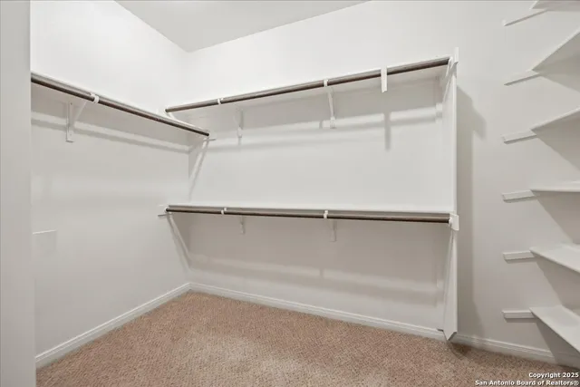 an empty room with chandelier fan and windows