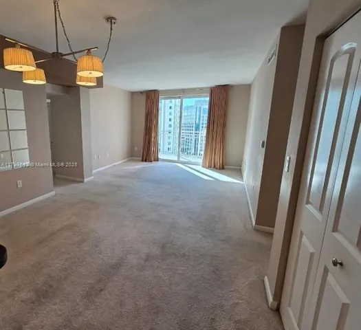 a view of empty room with window and refrigerator