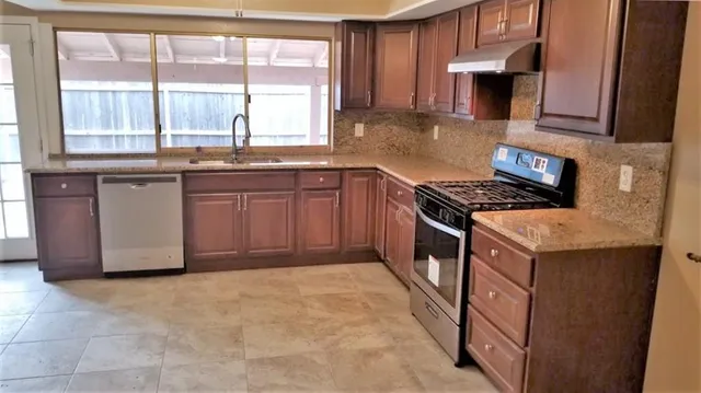 a kitchen with granite countertop a stove a sink and a microwave