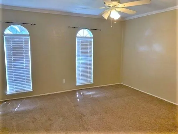 an empty room with windows and chandelier fan