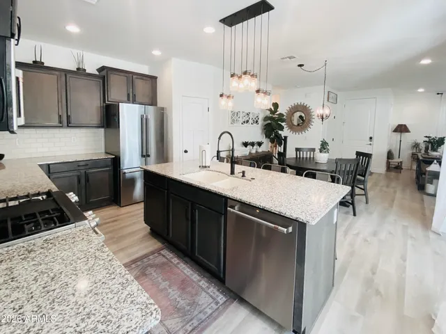 a kitchen with stainless steel appliances kitchen island granite countertop a sink a stove and a refrigerator