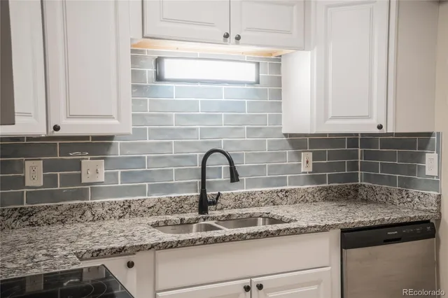a kitchen with granite countertop a sink and a white cabinets