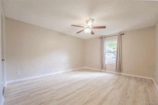 a view of an empty room with a window and a ceiling fan