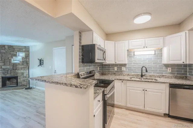 a kitchen with stainless steel appliances granite countertop a sink stove cabinets and wooden floor