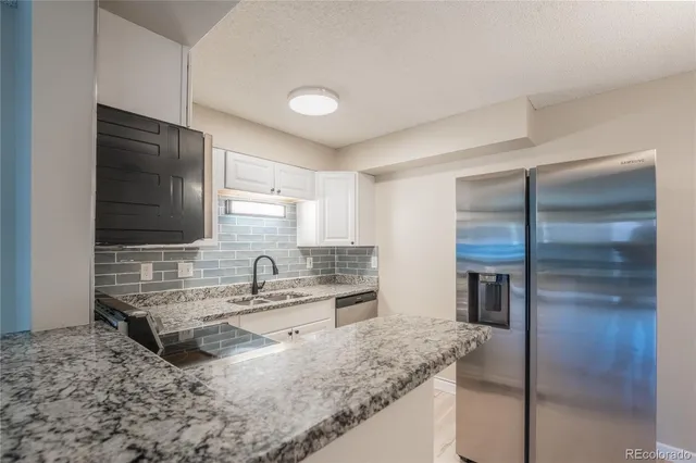 a kitchen with kitchen island granite countertop a sink and a refrigerator