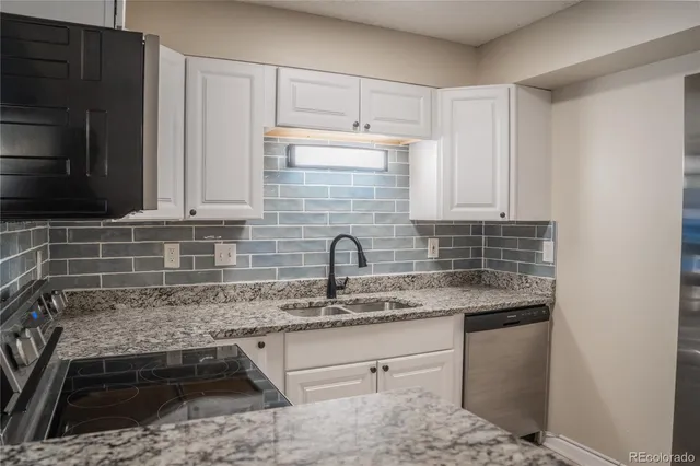 a kitchen with granite countertop a sink stainless steel appliances and cabinets