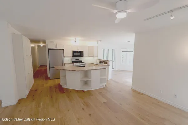 a kitchen with stainless steel appliances a refrigerator a stove a microwave oven with white cabinets and wooden floor