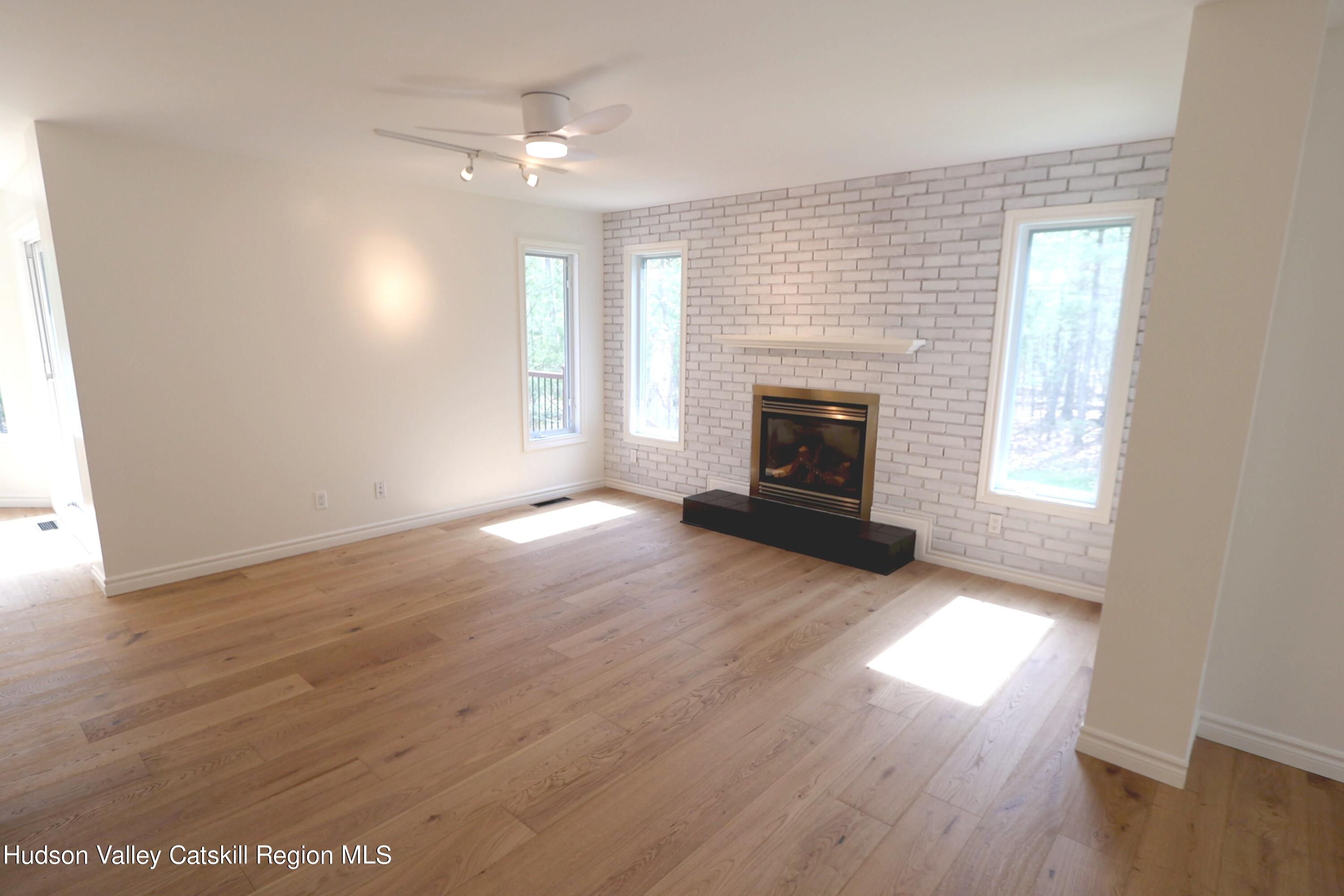 63 Lawrence Hill Road Accord, NY 12404 - Photo 14 of 27 an empty room with wooden floor fireplace and windows