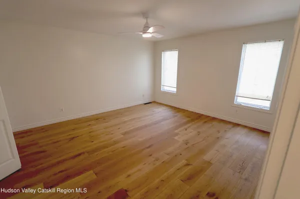 an empty room with wooden floor cabinet and windows