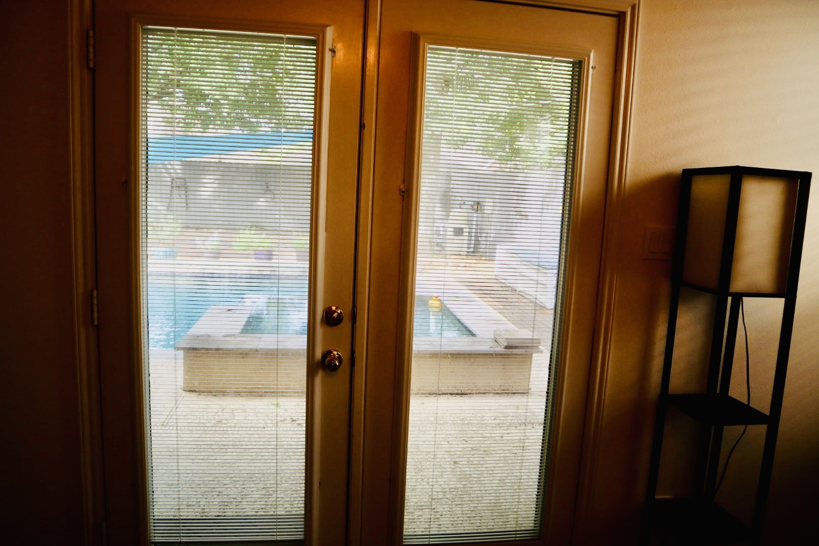 19114 Emory Trail Spring, TX 77388 - Photo 16 of 32 French doors with built-in blinds lead to a backyard with a swimming pool, providing a serene outdoor view.