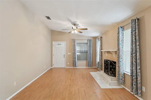 a view of a livingroom with a fireplace a ceiling fan and wooden floor