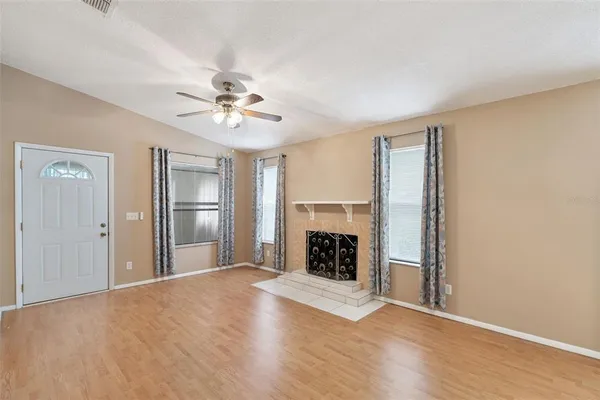 an empty room with windows and fireplace