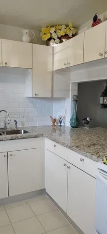 a kitchen with granite countertop white cabinets and a sink