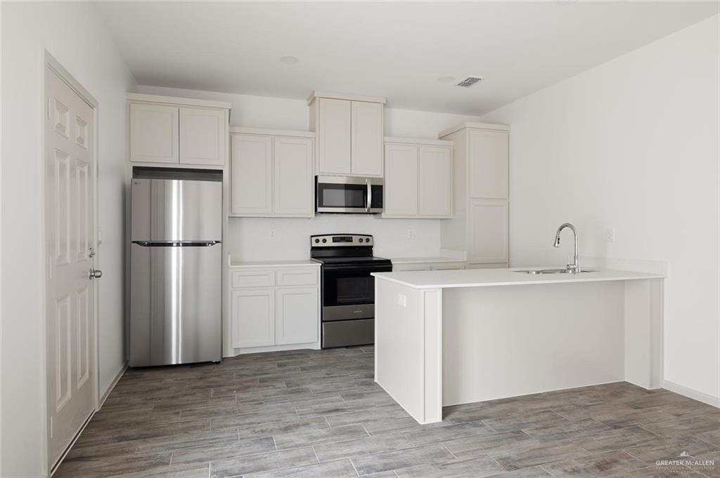 1308 Valle Vista Street, Unit 2 Alamo, TX 78516 - Photo 3 of 15 a kitchen with a refrigerator and a sink
