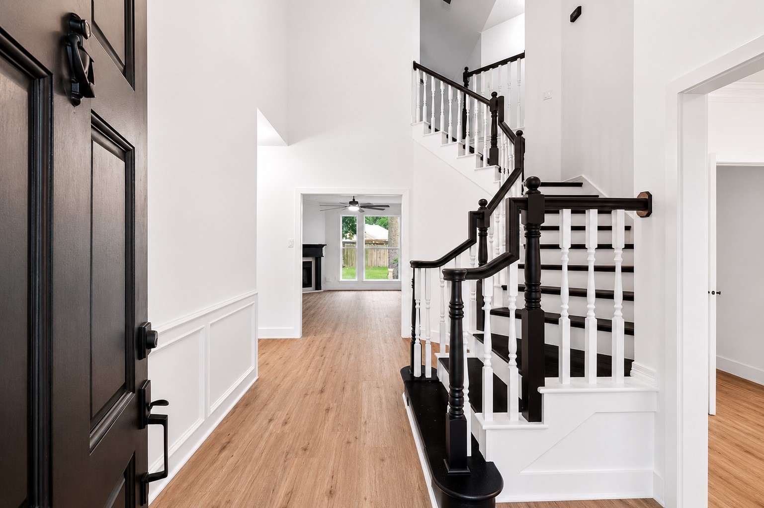 523 Rampart Lane Conroe, TX 77302 - Photo 3 of 41 Grand two story entry featuring soaring ceilings, elegant staircase with custom black and white railings, luxury vinyl plank flooring, and abundant natural light. This impressive foyer sets the tone for the home's sophisticated design and open concept layout.