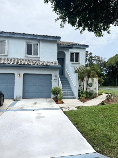 9778 Nickels Boulevard, Unit 504 Boynton Beach, FL 33436 - Photo 2 of 31 a front view of a house with a yard and garage