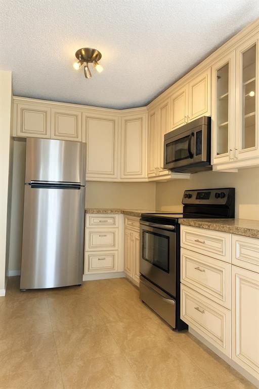 9778 Nickels Boulevard, Unit 504 Boynton Beach, FL 33436 - Photo 5 of 31 a kitchen with stainless steel appliances granite countertop a refrigerator a stove a microwave and cabinets