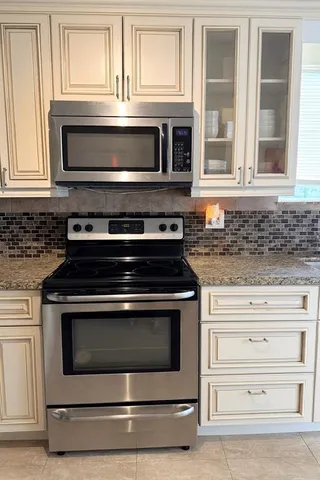a kitchen with granite countertop a stove microwave and oven