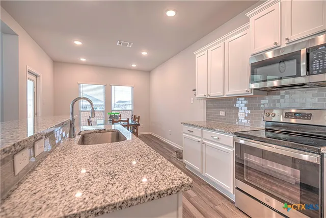 a kitchen with stainless steel appliances granite countertop a sink stove and cabinets