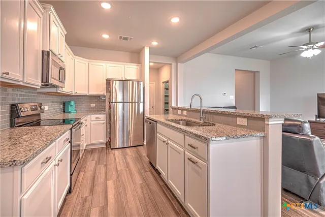 a kitchen with stainless steel appliances granite countertop a sink stove and refrigerator