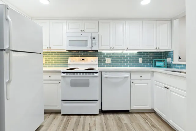 a kitchen with white cabinets and white appliances